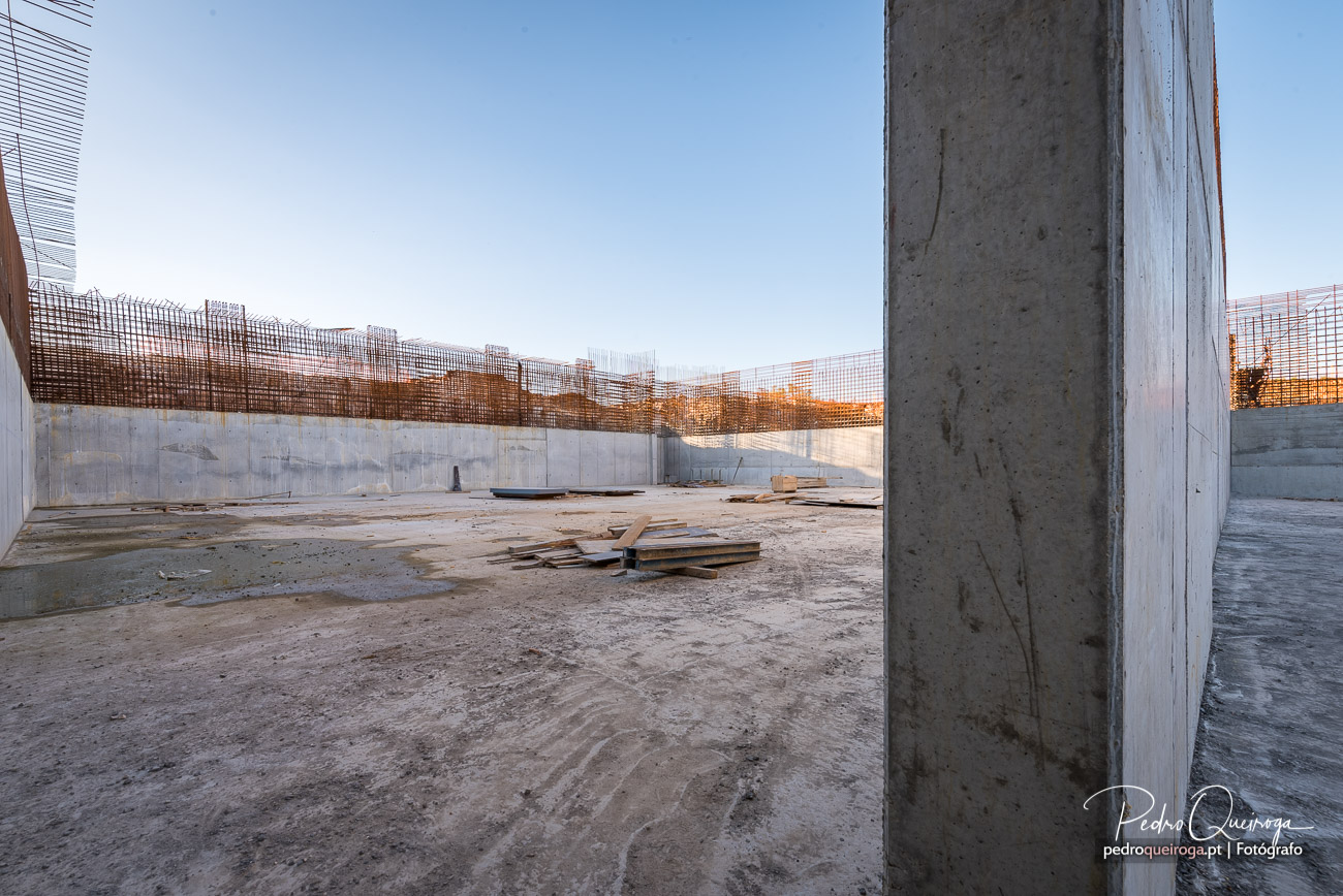 Interior de estrutura de betão em construção com paredes e armaduras de aço ao pôr do sol