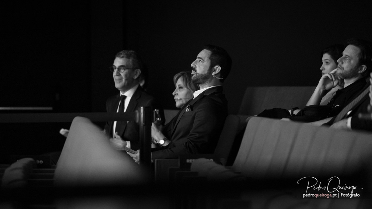 Convidados elegantes sentados numa sala de eventos, atentos e concentrados durante a cerimónia de casamento a preto e branco