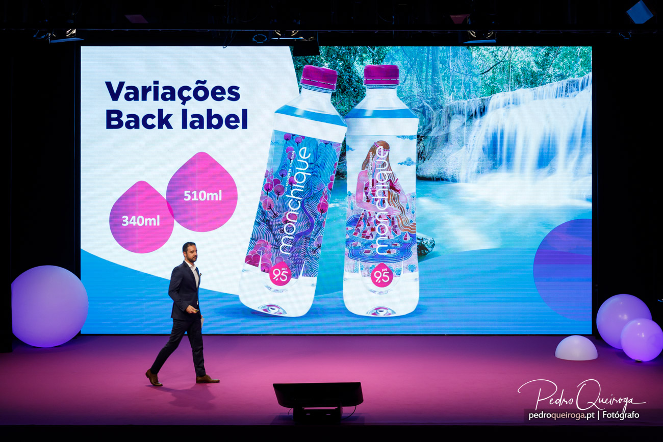 Apresentação corporativa com ecrã gigante a exibir garrafas de água Monchique e variações de embalagem back label
