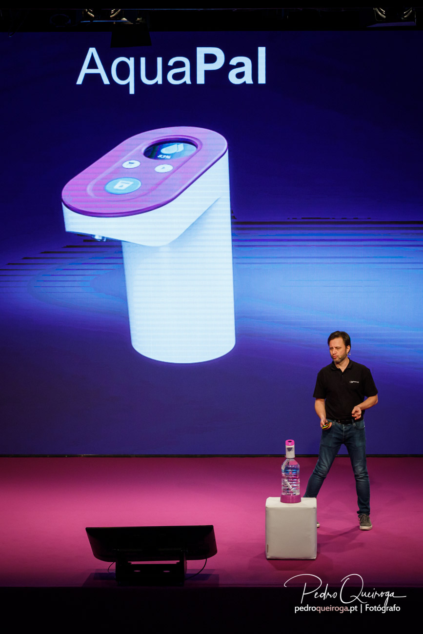 Apresentação do produto AquaPal num palco com fundo roxo e chão rosa vibrante durante evento corporativo