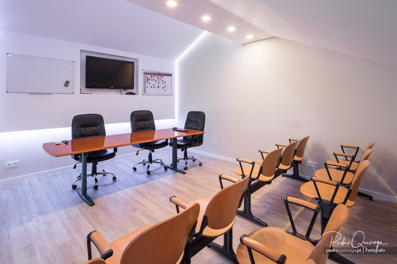 Sala de reuniões moderna com mesa, cadeiras e equipamento audiovisual ideal para empresas e hotéis