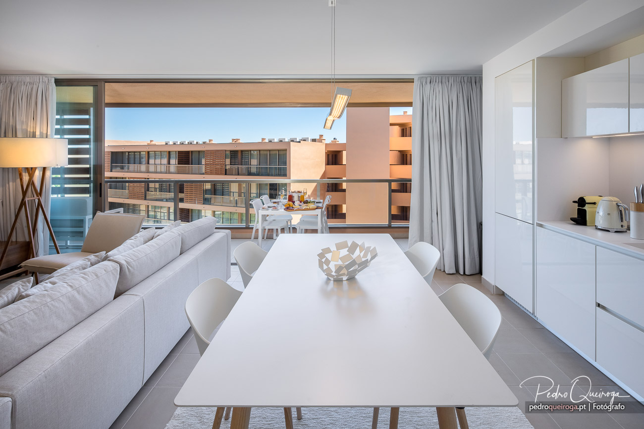 Apartamento moderno com sala ampla, cozinha integrada e varanda com vista para edifícios residenciais em tons claros