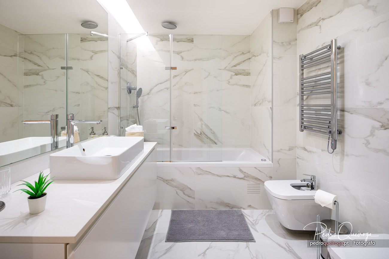 Casa de banho moderna com revestimento em mármore bege, banheira, duche e acabamentos dignos de hotel de luxo