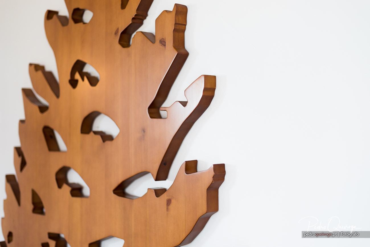 Peça decorativa em madeira com recortes vazados e contornos irregulares sobre fundo branco minimalista