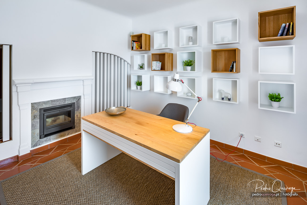 Escritório moderno com secretária em madeira, nichos brancos e madeira na parede, lareira e chão em terracota