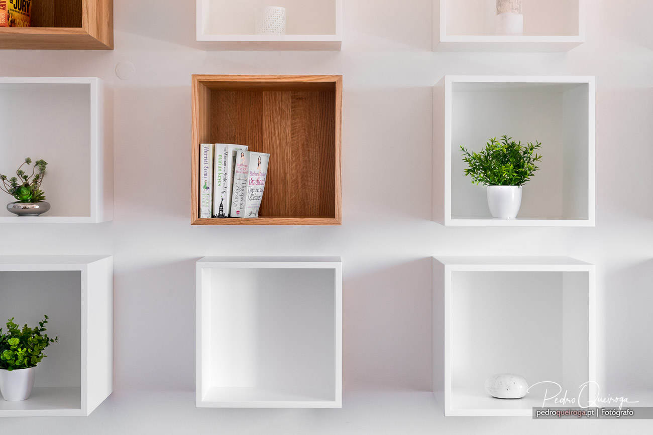 Estante moderna com nichos brancos e madeira, jornais e plantas decorativas, ideal para fotografia de imóveis