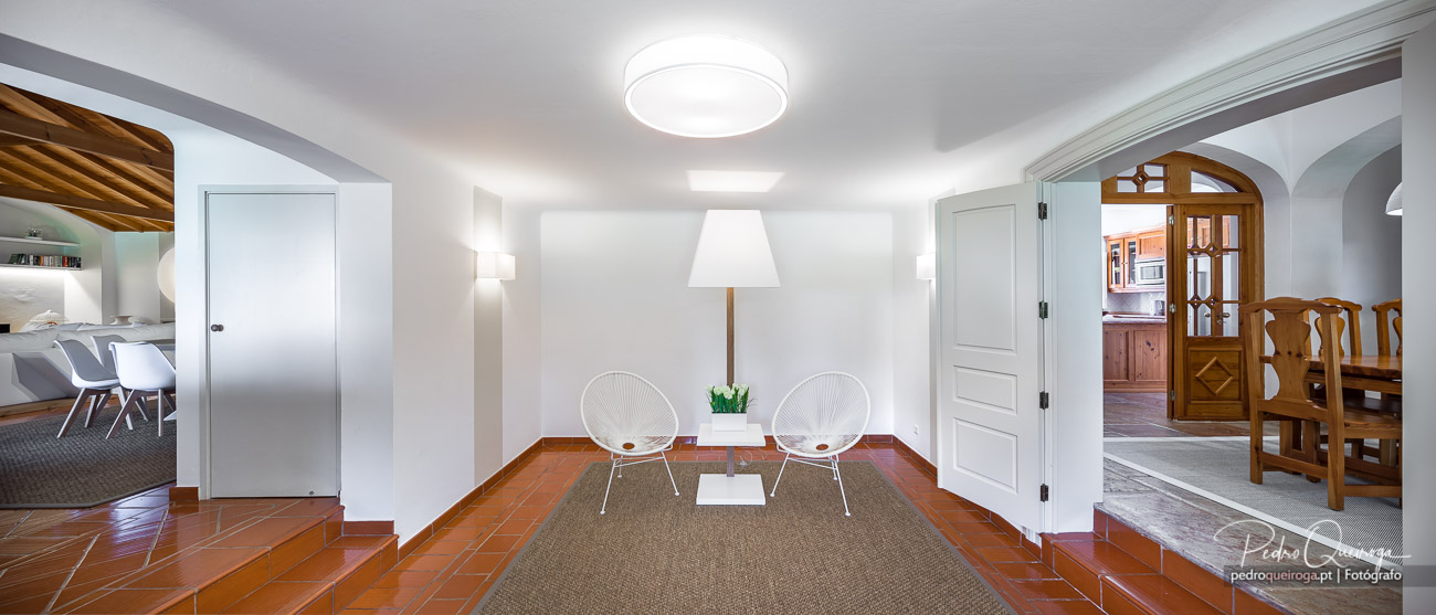 Sala de estar luminosa com cadeiras brancas e decoração minimalista, ideal para hotéis modernos e acolhedores.