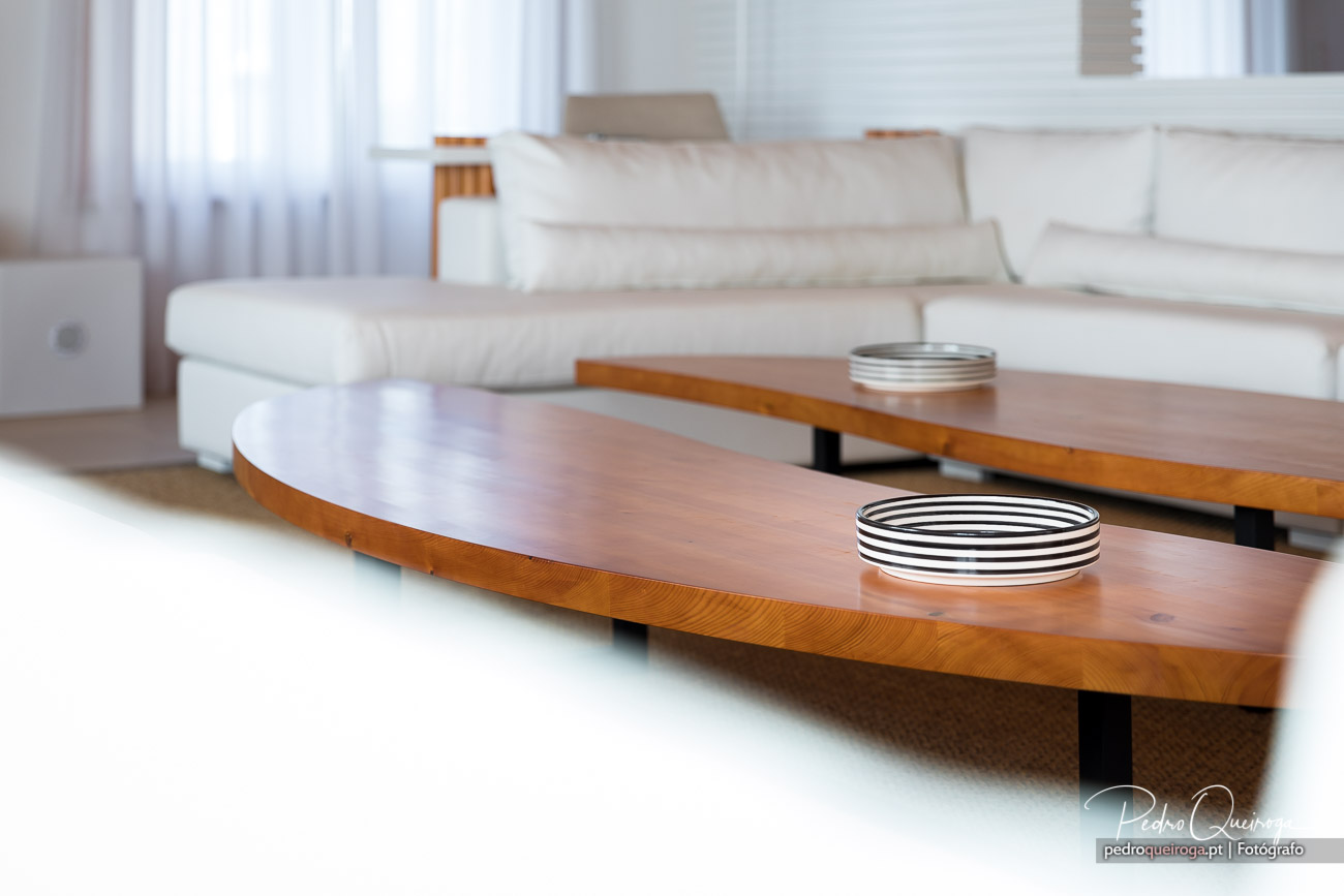Sala minimalista com mesas de madeira curvas e velas decorativas, ideal para composições fotográficas de interiores.