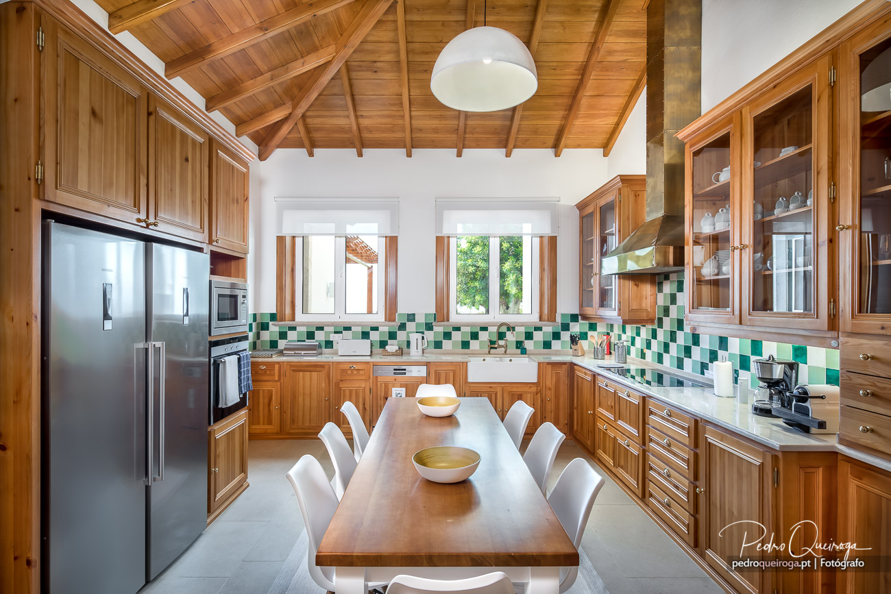 Cozinha ampla com madeira nobre, azulejos verdes e teto fotográfico que destaca a elegância do espaço interior.