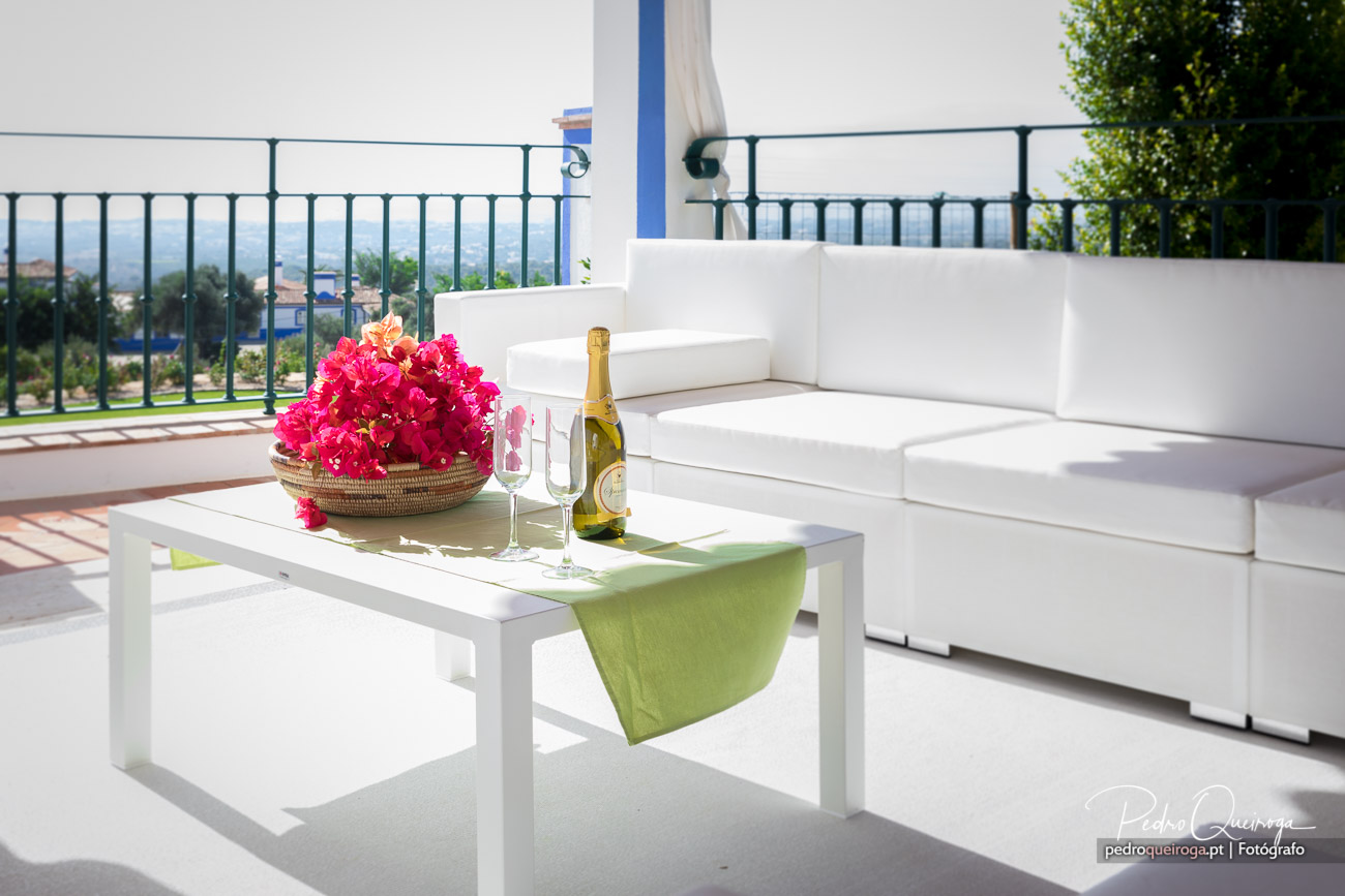 Terraço moderno com sofás brancos, mesa com flores vibrantes e champanhe, decoração elegante e vista panorâmica