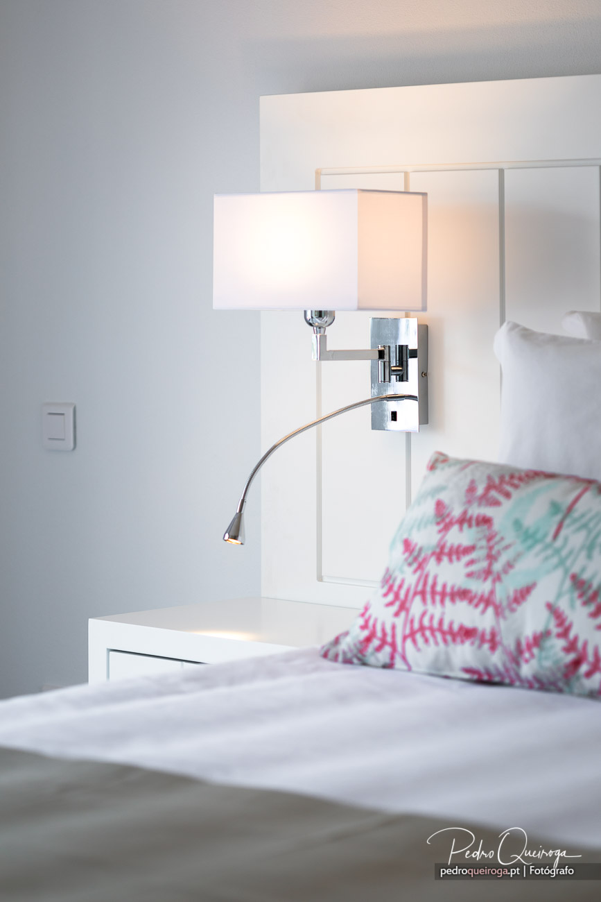 Candeeiro de parede cromado com luz suave num quarto minimalista, destacando a arquitetura de interiores moderna