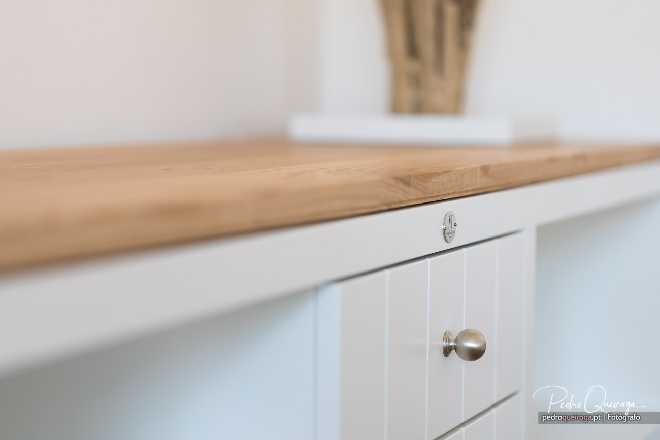 Detalhe de cozinha moderna com gavetas brancas e bancada em madeira, ideal para fotografias de interiores elegantes