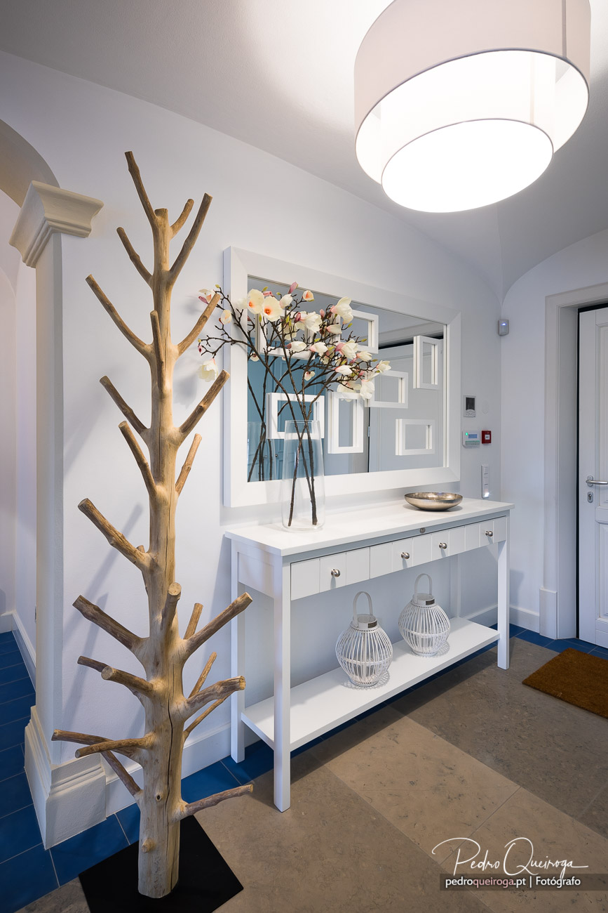Hall de entrada elegante com móvel branco, flores decorativas e árvore em madeira natural no Algarve