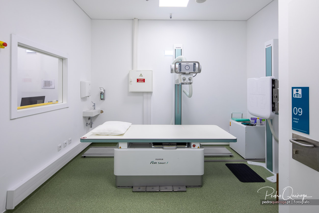 Sala de radiologia moderna com equipamento Fujifilm, paredes brancas e pavimento verde em ambiente clínico limpo