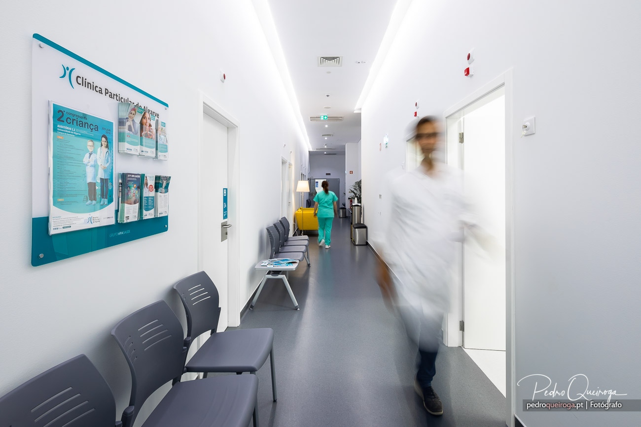 Corredor moderno de clínica com profissionais de saúde em movimento, ideal para portfólios imobiliários e corporativos