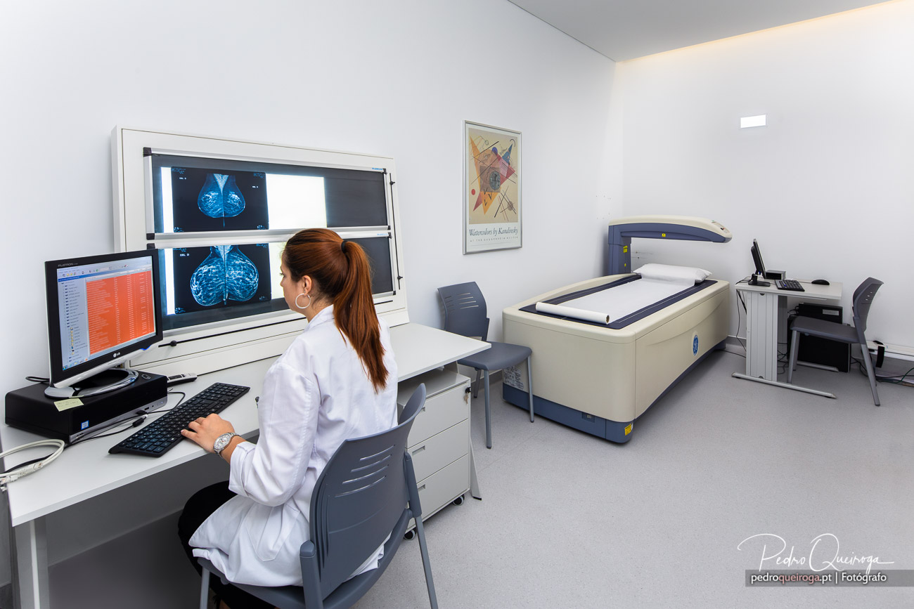 Profissional de saúde analisa mamografias em sala clínica moderna com equipamento de imagiologia médica