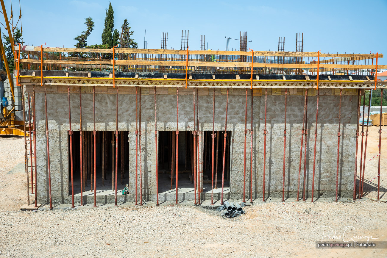 Estrutura de betão armado com escoramento metálico e cofragem de madeira em fase de construção em estaleiro a céu aberto