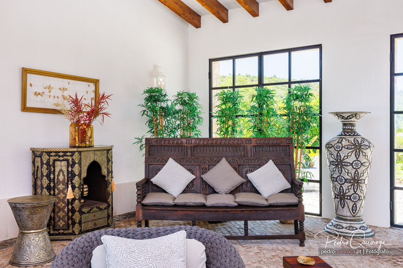 Sala de estar com sofá de madeira trabalhada, plantas tropicais e decoração étnica capturada pelo fotógrafo