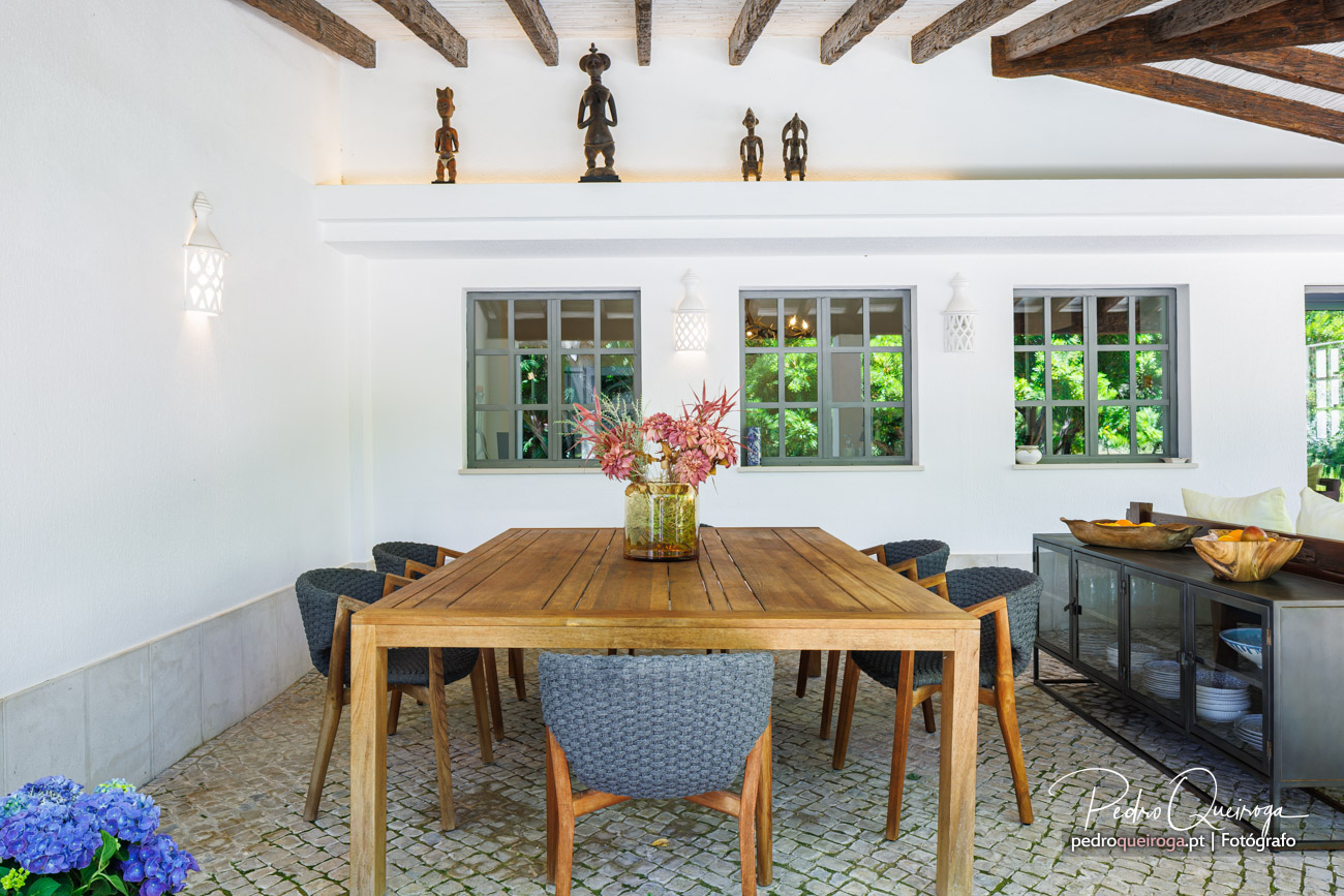 Sala de refeições elegante com vigas de madeira e esculturas africanas, ideal para fotografia de hotéis boutique.