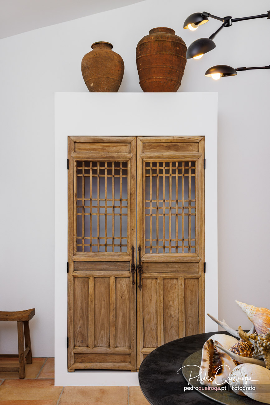 Porta de madeira antiga com gradil, ânforas rústicas e candeeiros modernos em fotografia imobiliária de interiores