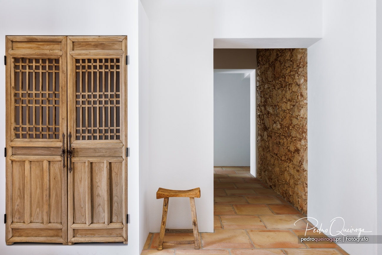 Portas de madeira com grade, banco rústico e pilar em cortiça numa casa típica do Algarve