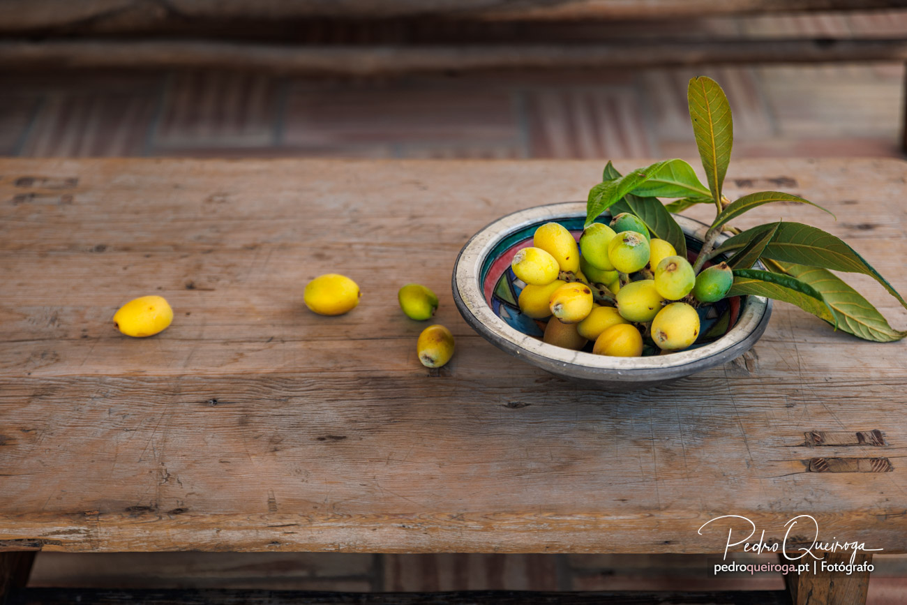 Tigela rústica com frutos amarelos e verdes sobre mesa de madeira envelhecida, composição natural e orgânica