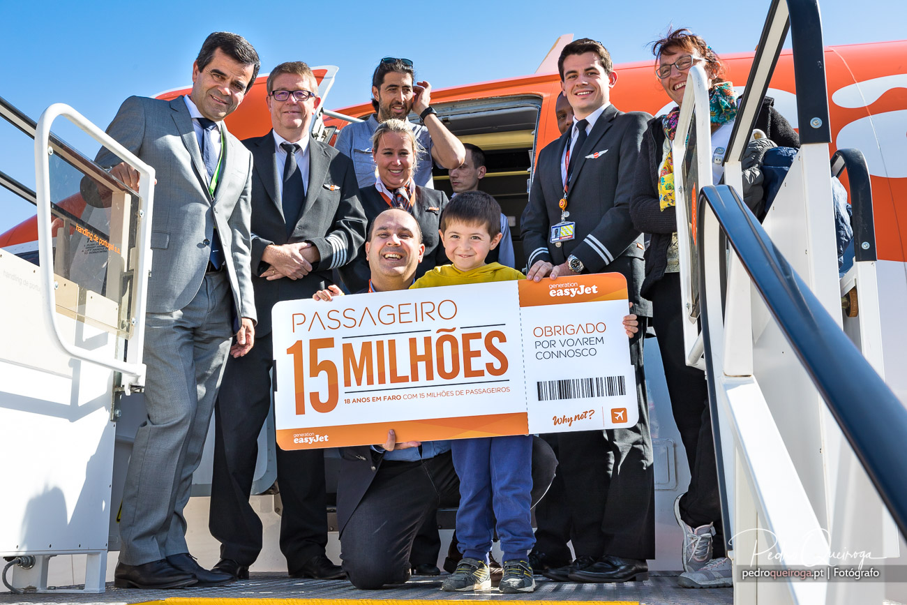Tripulação e passageiros celebram o 15 milhões de passageiros da easyJet à saída de um avião laranja.