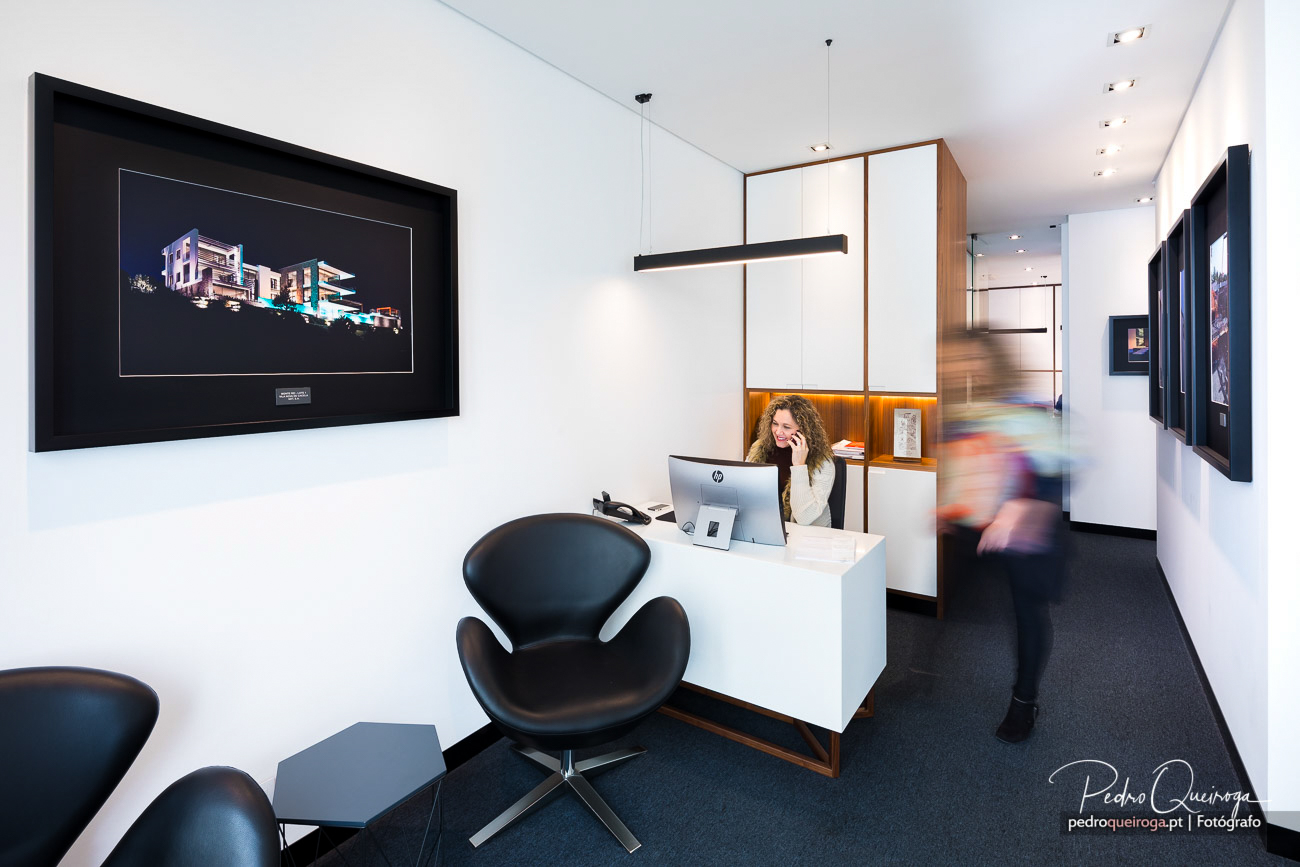 Rececionista ao telefone em escritório moderno no Algarve, com design minimalista e fotografia emoldurada na parede