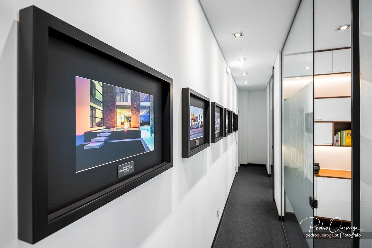 Corredor moderno com galeria de fotografias emolduradas, ideal para espaços corporativos ou hotéis de luxo.