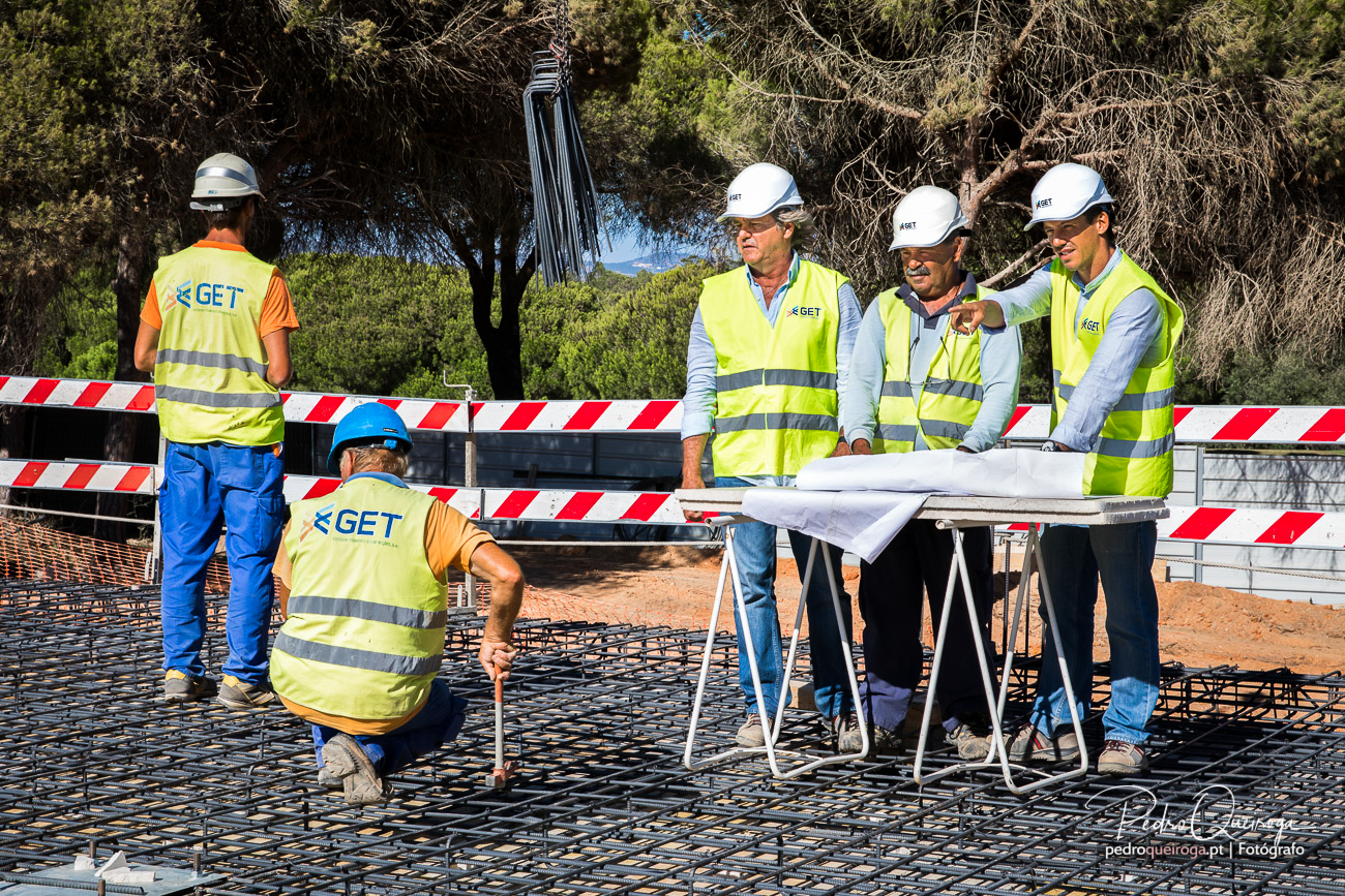 Equipa de engenheiros em obra a analisar planta técnica, fotografias de ambiente corporativo em construção civil