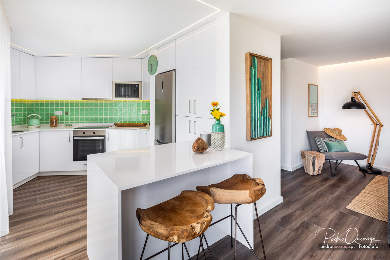 Cozinha moderna com mosaico verde, bancos de madeira e sala adjacente com detalhes turquesa em fotografia de interiores