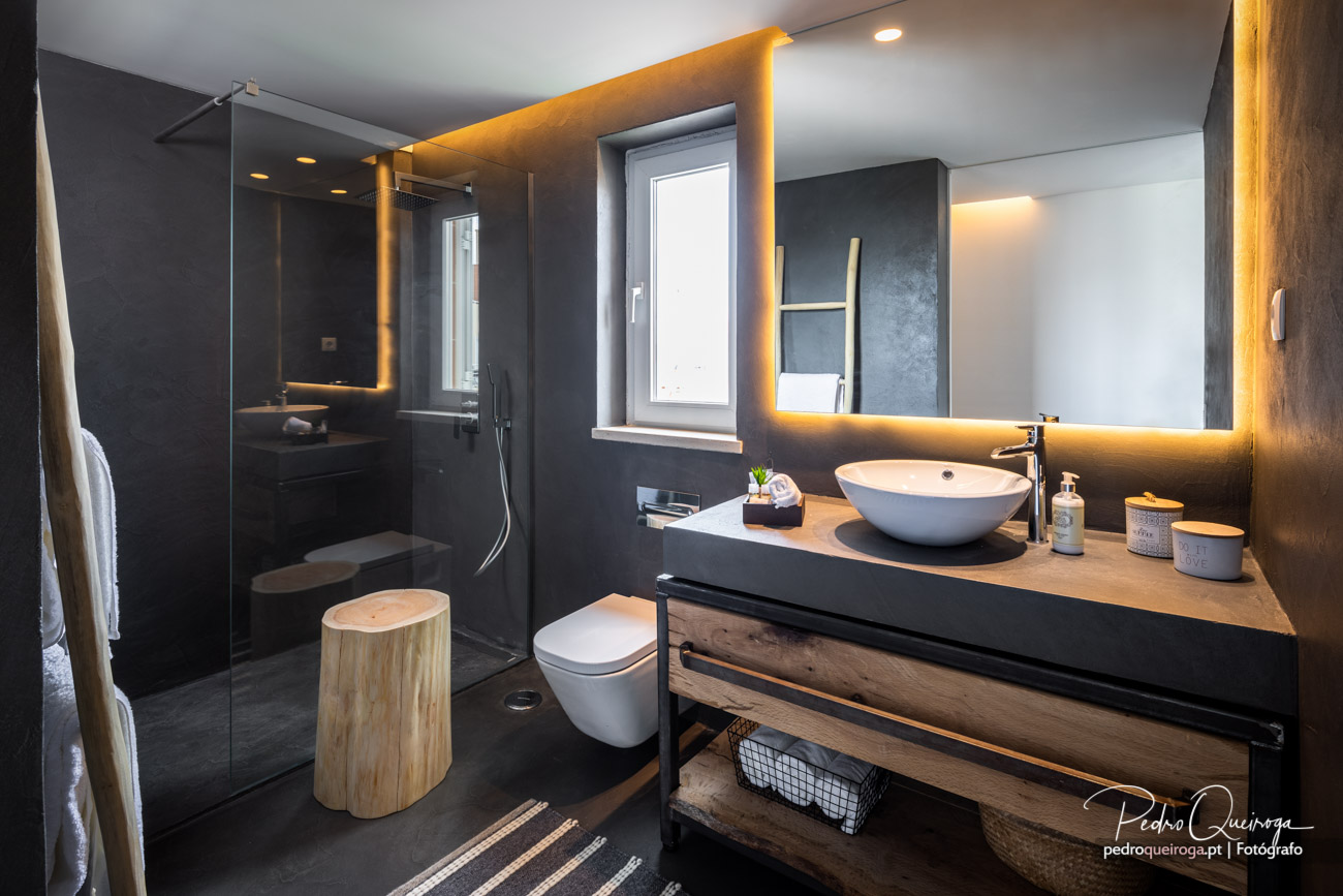Casa de banho moderna com paredes escuras, iluminação LED ambiente, espelho retroiluminado e duche em vidro