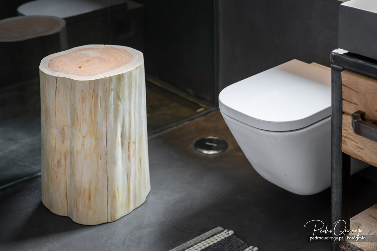Casa de banho moderna com tronco de madeira natural, sanita suspensa branca e pavimento cinza escuro