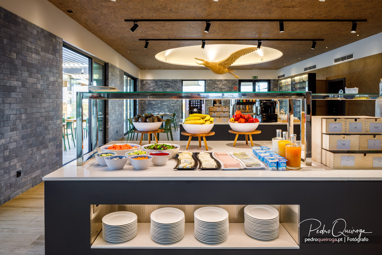 Buffet de pequeno-almoço de hotel com fruta fresca, sumos naturais e pratos organizados sob iluminação moderna