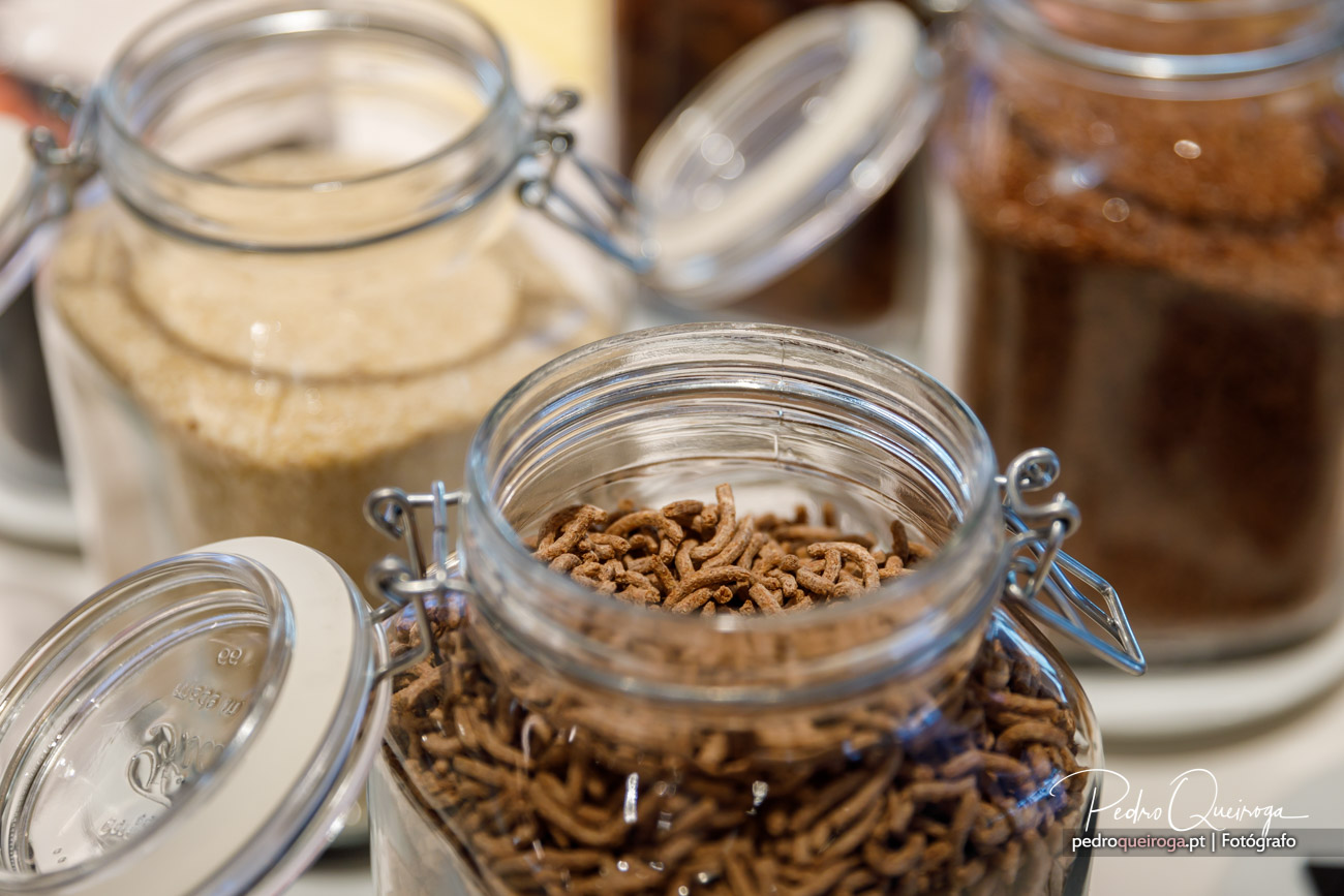 Frascos de vidro com cereais de chocolate e ingredientes diversos numa bancada de cozinha bem iluminada