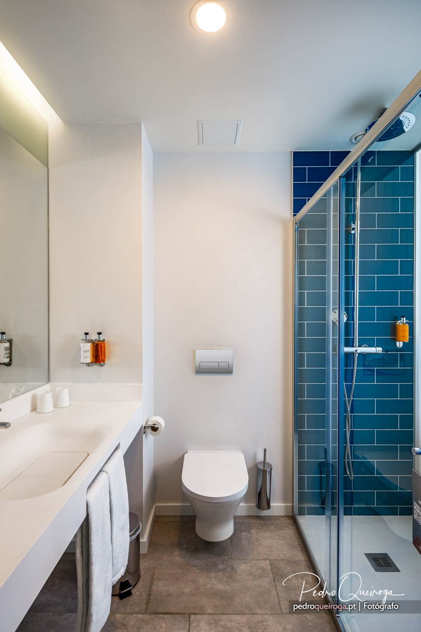 Casa de banho moderna com azulejos azuis na zona de duche e decoração minimalista em tons claros e neutros