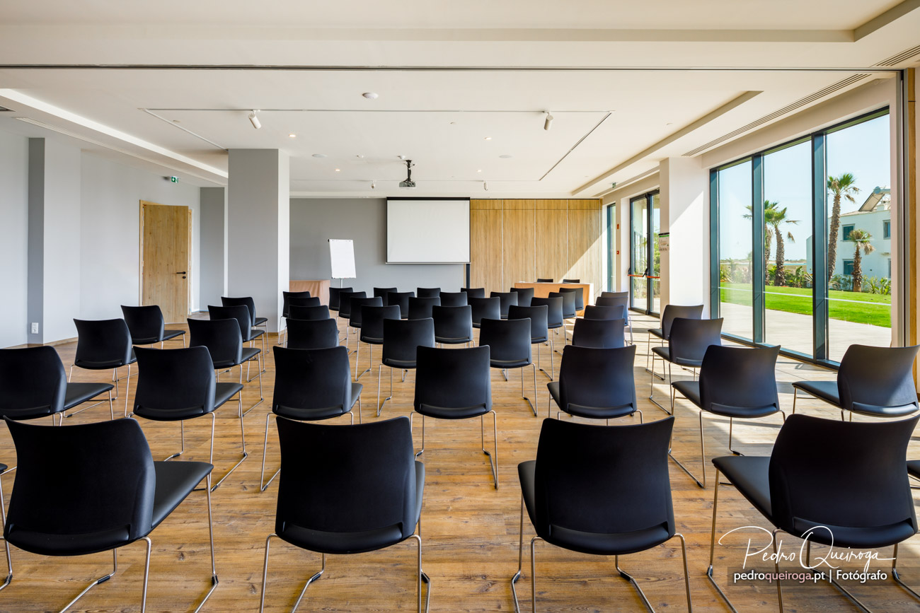 Sala de conferências moderna com cadeiras pretas, projetor e vista para jardim em composição fotográfica luminosa