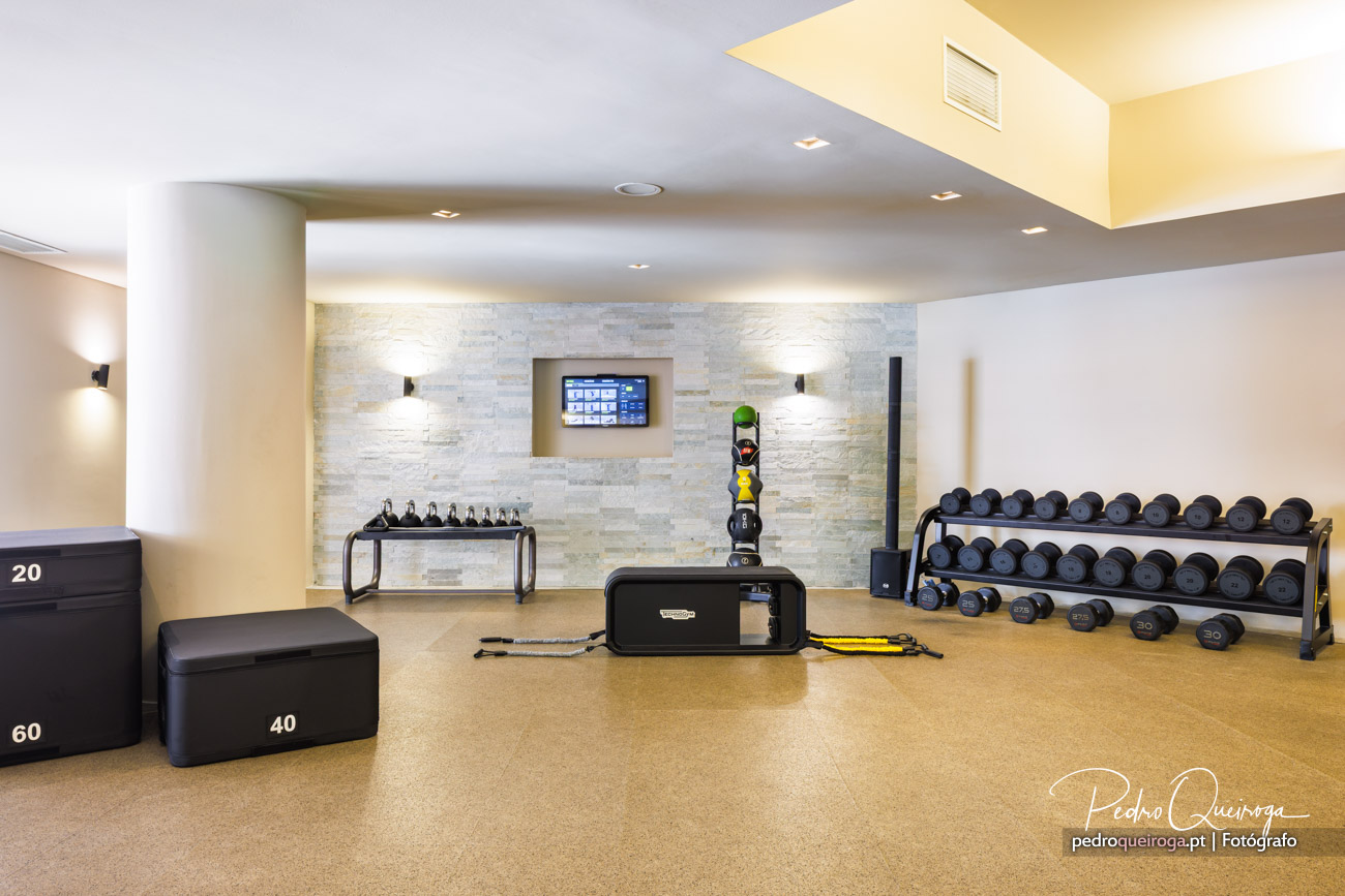 Ginásio moderno com halteres, caixas de treino e parede em pedra, ideal para hotéis de luxo