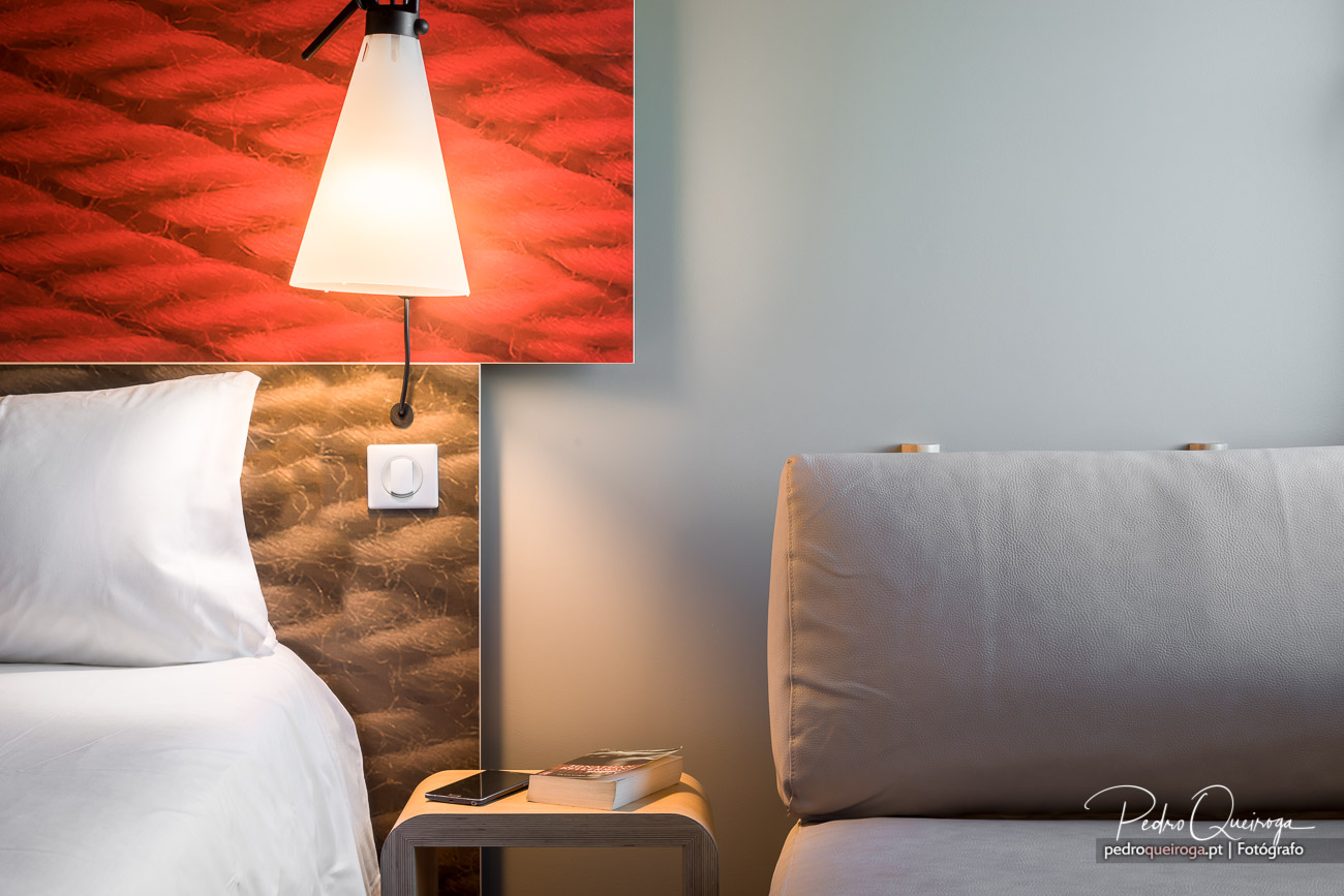 Quarto moderno com candeeiro iluminado, parede texturizada avermelhada, sofá cinza e ambiente acolhedor e contemporâneo.