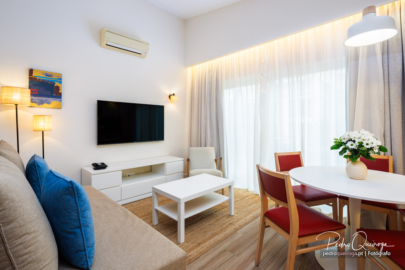 Sala moderna e luminosa com detalhes fotográficos que destacam o mobiliário branco e cadeiras vermelhas elegantes