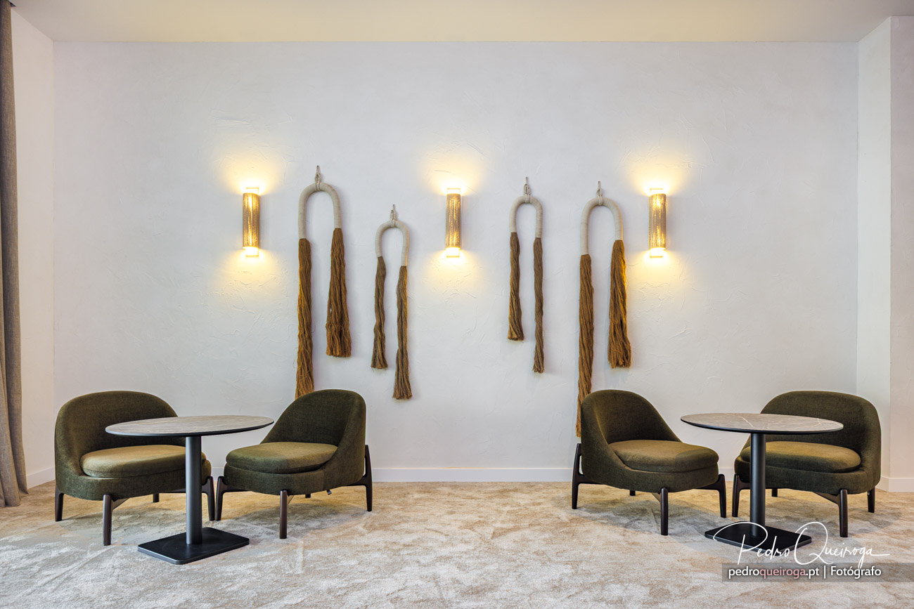 Sala de estar moderna com cadeiras verdes, mesas redondas e apliques decorativos em corda na parede branca