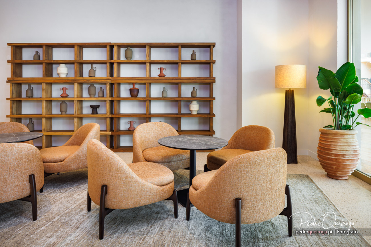 Sala de estar elegante com cadeiras laranja, estante de madeira e decoração cerâmica captada por fotógrafo de interiores