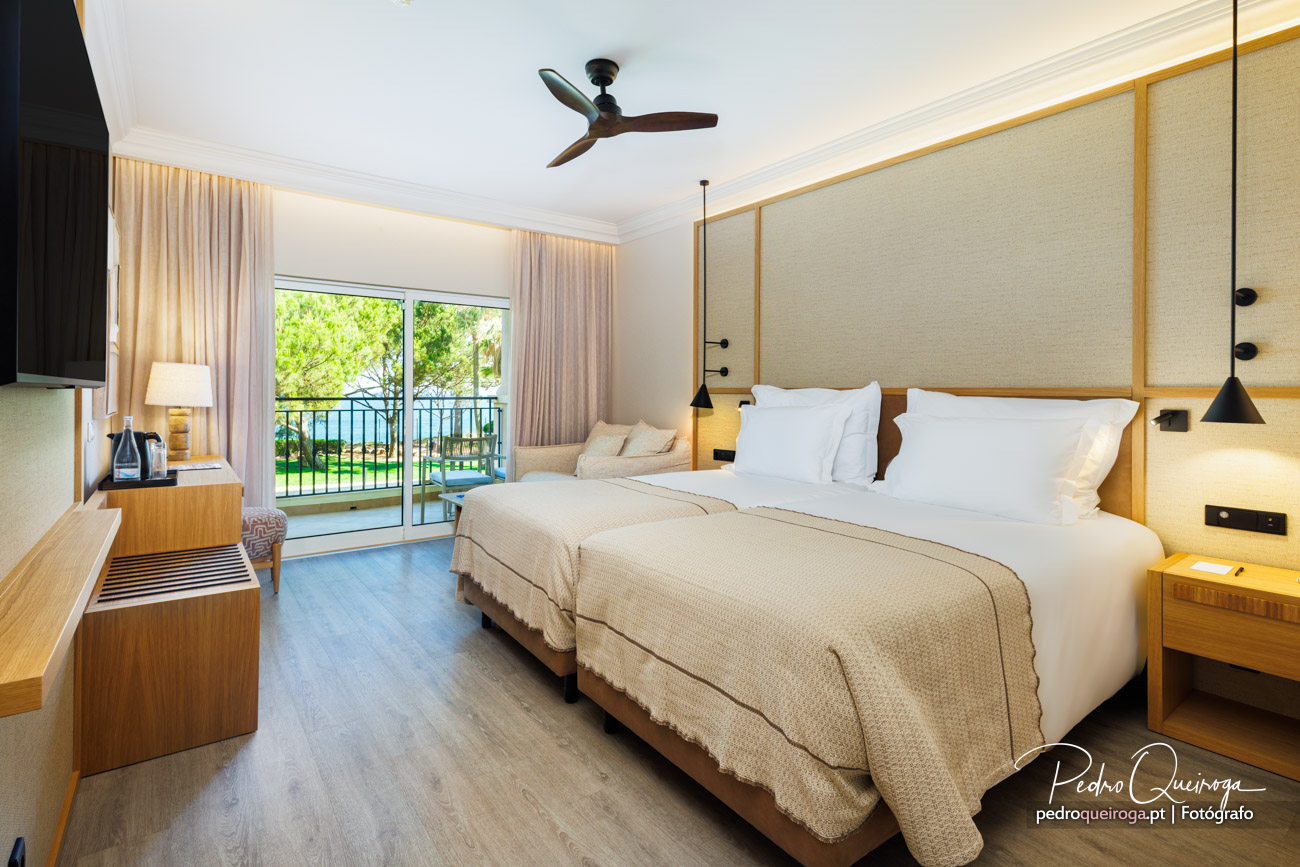 Quarto de hotel luminoso com duas camas, decoração em tons neutros e varanda com vista para o jardim exterior