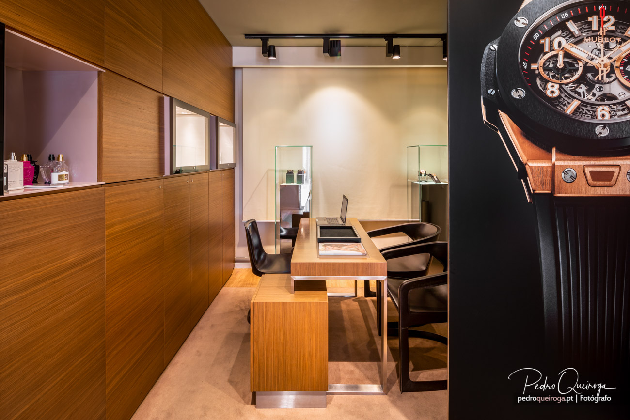 Interior elegante de loja de relógios com móveis em madeira, vitrines de vidro e zona de atendimento sofisticada