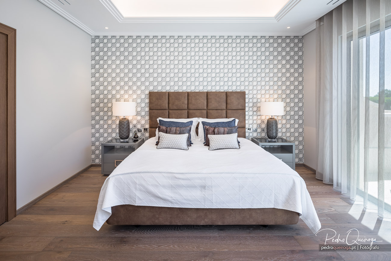 Quarto elegante com papel de parede texturizado e cabeceira almofadada em fotografias de interiores contemporâneos