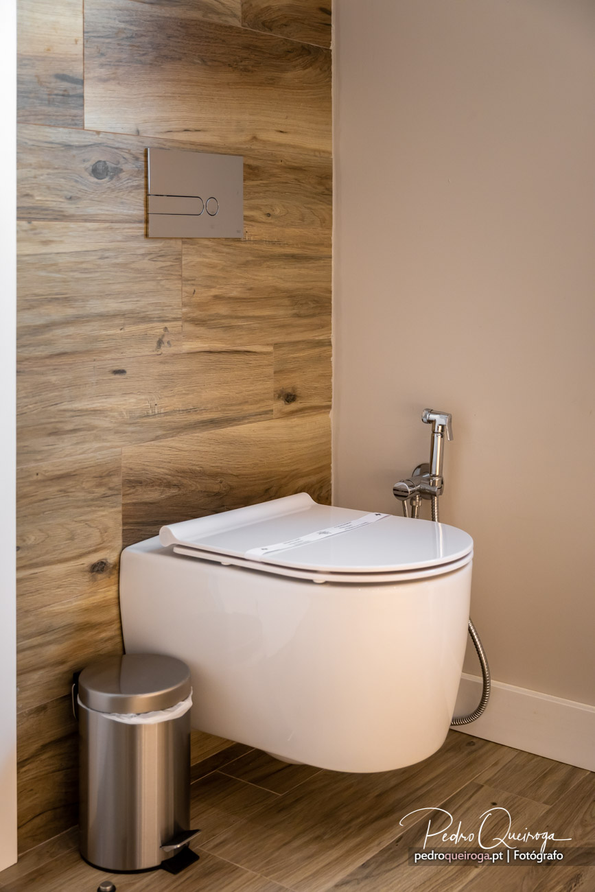 Casa de banho moderna com sanita suspensa branca, revestimento em madeira natural e parede bege suave