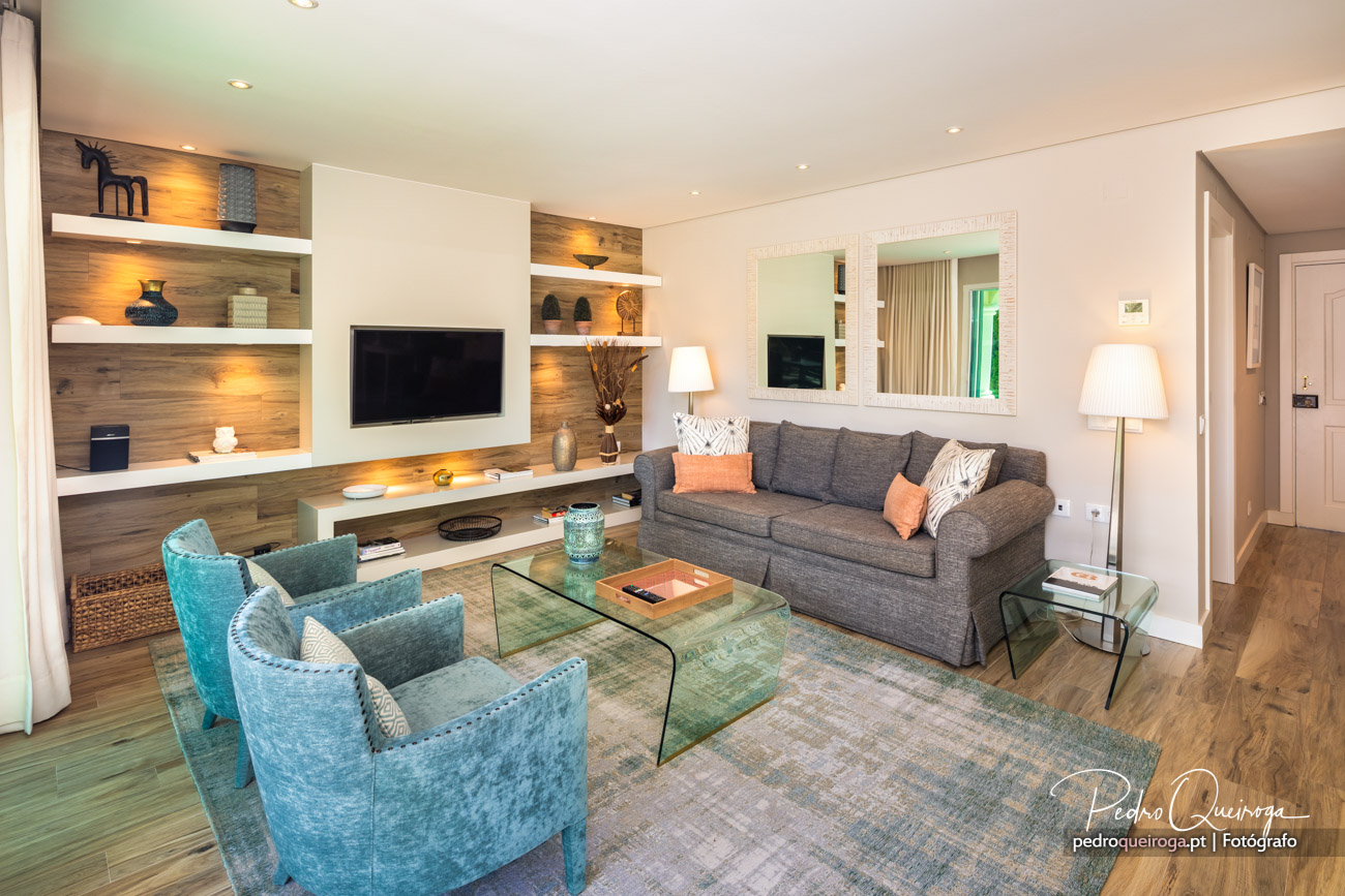 Sala de estar moderna com sofás turquesa e cinza, destacando a arquitetura de interiores com nichos iluminados.