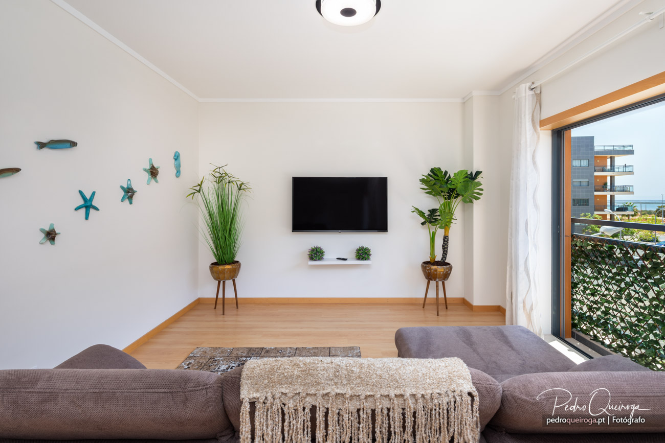 Sala luminosa com decoração marítima, ideal para anúncios imobiliários, com varanda e vista desafogada.