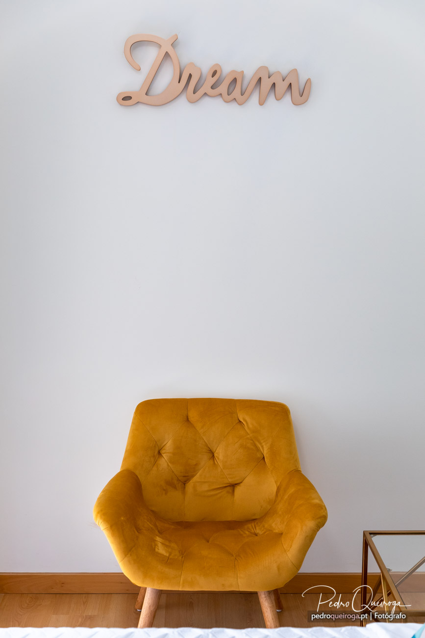Poltrona amarela em veludo capitoné sob parede branca com lettering Dream em madeira rosé