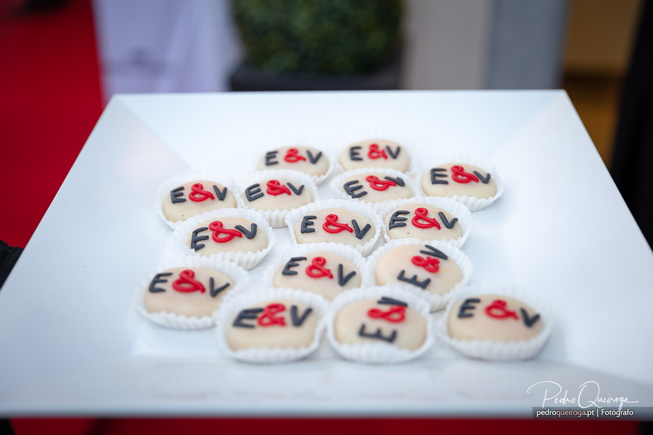 Bolachas personalizadas com letras E e V decoradas em vermelho e preto dispostas sobre mesa branca